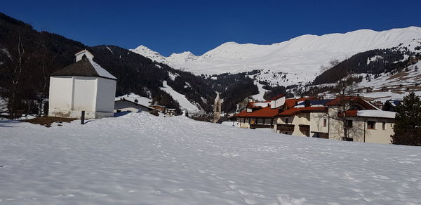 Snow covered landscape and mountains against clear sky