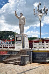 Statue of man standing on bridge against cloudy sky