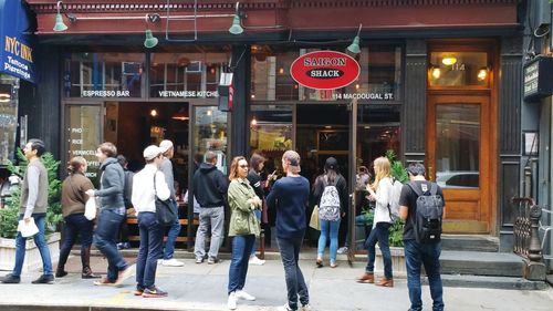 People walking on street against buildings in city