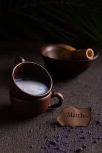 Cups of blue matcha tea with milk and powdered tea on the table