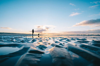 Man on beach against sky during sunset