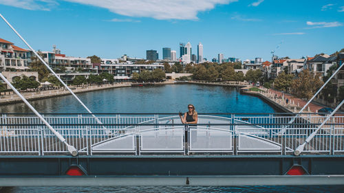 Bridge over river in city against sky