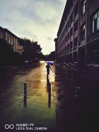 Boy in wet city against sky