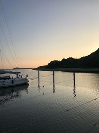 Sailboats moored in sea against clear sky during sunset