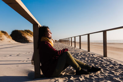 Young woman with eyes closed relaxing at beach at sunset. holidays and relaxation concept