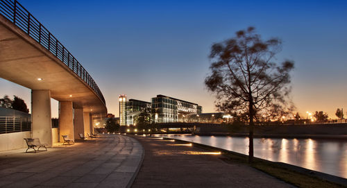 Illuminated bridge over river in city against sky