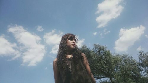 Low angle view of woman standing against blue sky