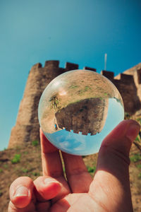 Close-up of person holding ice cream against blue sky