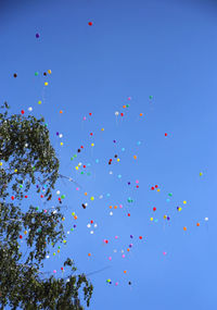 Low angle view of balloons flying against clear blue sky