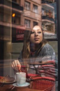 Woman sitting in cafe seen through glass 