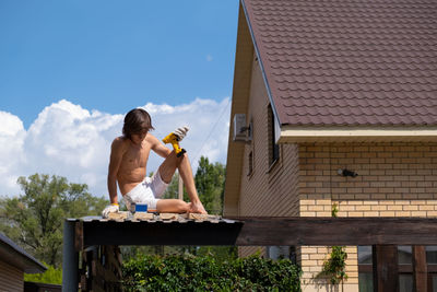 Building roof. young men repair roof. roof construction. working at height with a screwdriver.