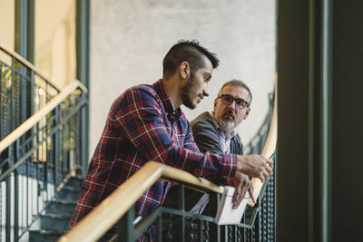 Mature businessman discussing with coworker on staircase in office