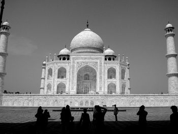 People in front of historical building against clear sky