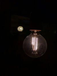 Low angle view of lit light bulb at night