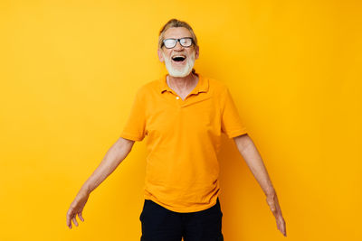 Smiling senior man against yellow background