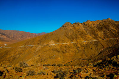 Scenic view of mountains against clear blue sky