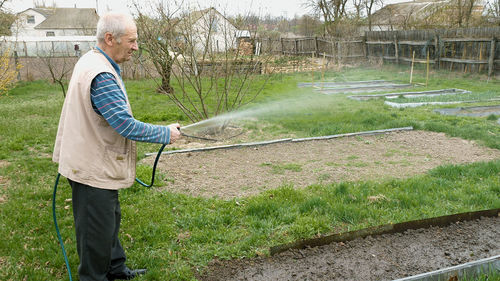 Side view of senior man watering at farm