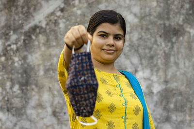 Selective focus on an indian woman in yellow dress holding homemade cotton mask