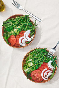 Healthy vegan salad with tomatoes, arugula, avocado, spinach red onion and olive oil. summer brunch