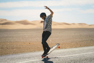 Man skateboarding on road during sunny day