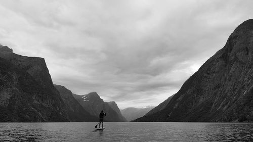 Man paddleboarding in sea against mountains