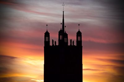 Exterior of silhouette church against orange cloudy sky during sunset