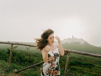 Woman standing by railing against sky