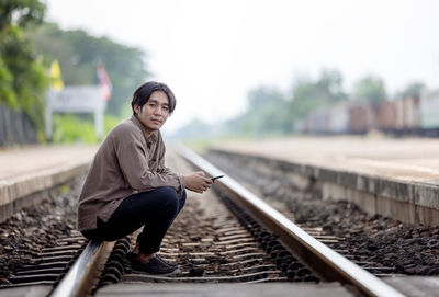 Depressed young man sitting on railway track person