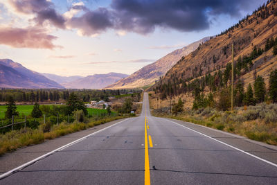 Road leading towards mountains against sky