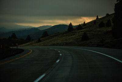 Road by mountains against sky at dusk