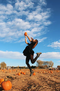 Low angle view of woman jumping against sky