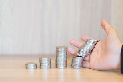 Cropped image of hand holding coins on table