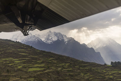 Mountain scene and terraces viewed past wing of a small plane, nepal