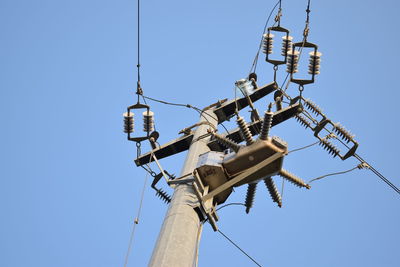 Low angle view of telephone pole against clear blue sky