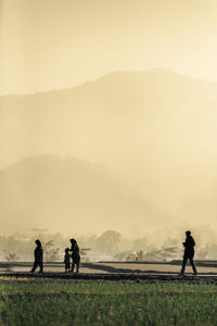 People on field against sky during foggy weather