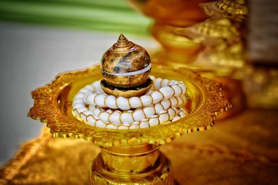 Close-up of gold colored lamp on table