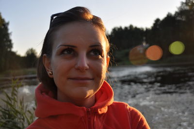 Close-up of smiling young woman against lake