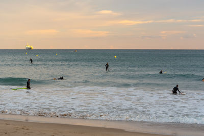 People on beach against sky during sunset