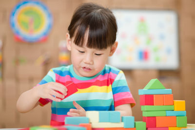 Young girl playing toy blocks at home 