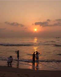 People on beach against sky during sunset