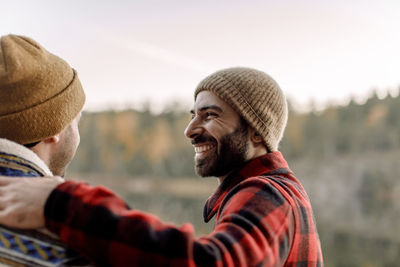 Side view of happy man with beard looking at male friend