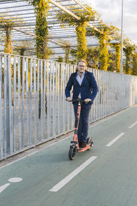 Businessman riding push scooter on road