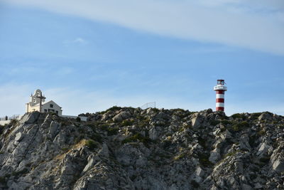 Lighthouse by buildings against sky