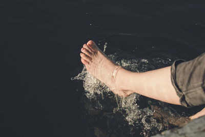 Low section of woman splashing water in sea