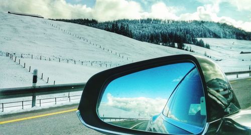 Reflection of sky on side-view mirror of car