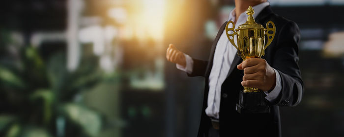 Digital composite image of woman holding trophy