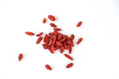 High angle view of red berries on white background