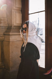 Woman wearing sunglasses standing against door