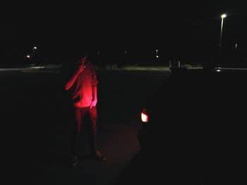 Man standing by illuminated light at night