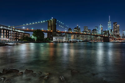 Illuminated bridge over river in city at night